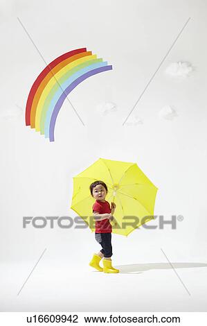 Stock Image - Boy with Yellow Umbrella Under Rainbow. Fotosearch
