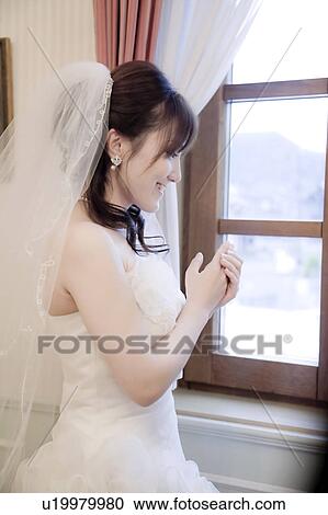 Stock Image - Bride standing by the window. Fotosearch