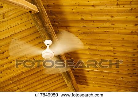 Stock Image - Ceiling fan turning in a log cabin. Fotosearch