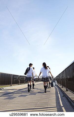 Stock Image - Four Schoolgirls Walking on Bridge. Fotosearch
