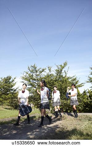 Stock Image - Four Teenage Schoolgirls Walking in Park. Fotosearch