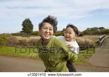 Stock Image - Grandmother Carrying Granson. Fotosearch