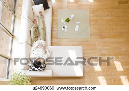 Man relaxing on sofa View Large Photo Image Stock Photo - Man relaxing on sofa. Fotosearch