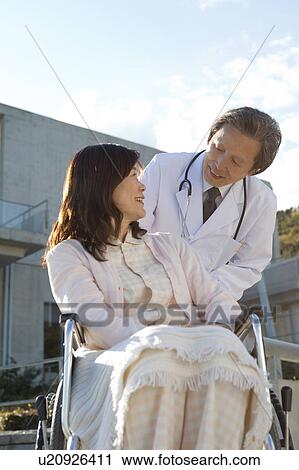 Stock Image - Mature Woman in Wheelchair and Male Doctor. Fotosearch