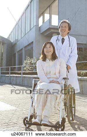 Stock Image - Mature Woman in Wheelchair and Male Doctor Looking Up. Fotosearch