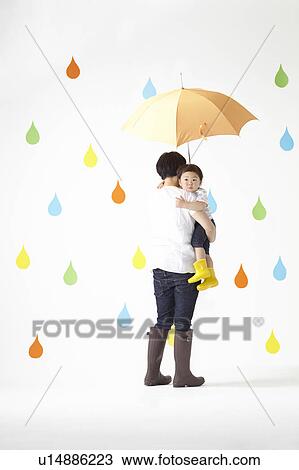 Stock Image - Mother Carrying Son in Rain. Fotosearch