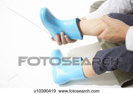 Mother helping son wear rubber boots View Large Photo Image Stock Photo - Mother helping son wear rubber boots. Fotosearch