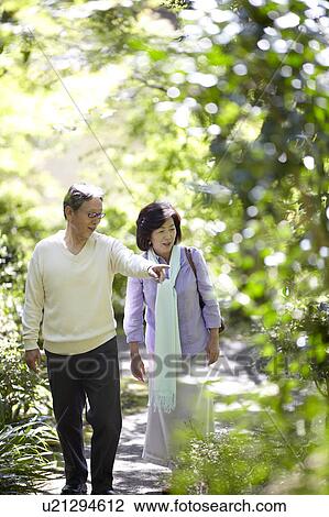 Stock Image - Senior Couple Walking and Talking on Path. Fotosearch