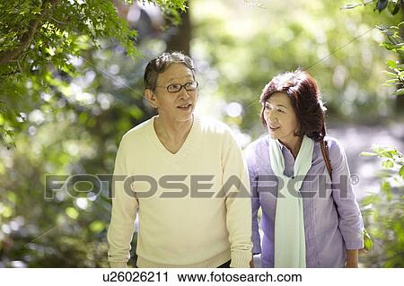 Stock Image - Senior Couple Walking and Talking on Path. Fotosearch