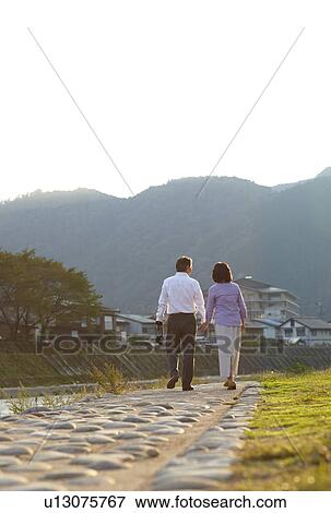 Stock Photo - Senior Couple Walking by River. Fotosearch