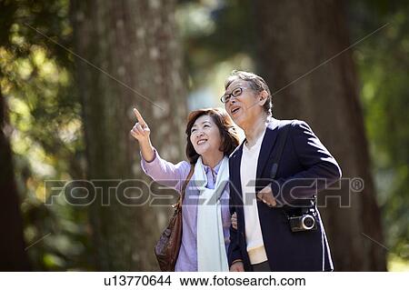 Picture - Senior Couple Walking in Park and Pointing. Fotosearch