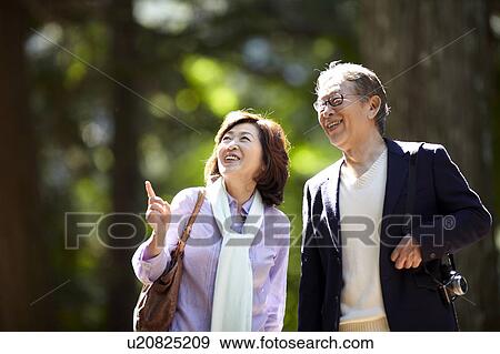 Stock Photo - Senior Couple Walking in Park and Pointing. Fotosearch