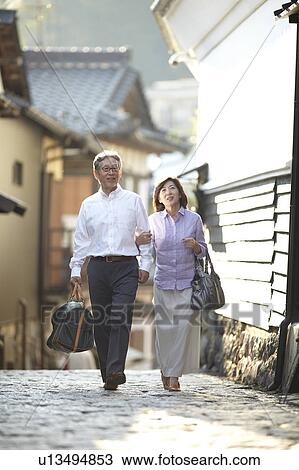 Stock Image - Senior Couple Walking in Village. Fotosearch