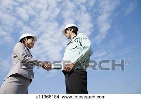 Two Businesspeople with Hardhats Shaking Hands View Large Photo Image Picture - Two Businesspeople with Hardhats Shaking Hands. Fotosearch