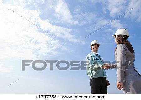 Two Businesspeople with Hardhats Shaking Hands View Large Photo Image Stock Image - Two Businesspeople with Hardhats Shaking Hands. Fotosearch