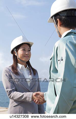 Two Businesspeople with Hardhats Shaking Hands View Large Photo Image Stock Photo - Two Businesspeople with Hardhats Shaking Hands. Fotosearch