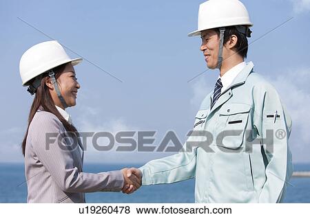 Two Businesspeople with Hardhats Shaking Hands View Large Photo Image Stock Photo - Two Businesspeople with Hardhats Shaking Hands. Fotosearch
