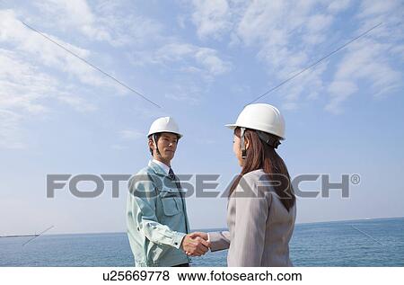 Two Businesspeople with Hardhats Shaking Hands View Large Photo Image Stock Photo - Two Businesspeople with Hardhats Shaking Hands. Fotosearch