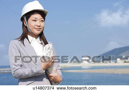 Picture - Young Businesswoman with Blueprint and Hardhat. Fotosearch