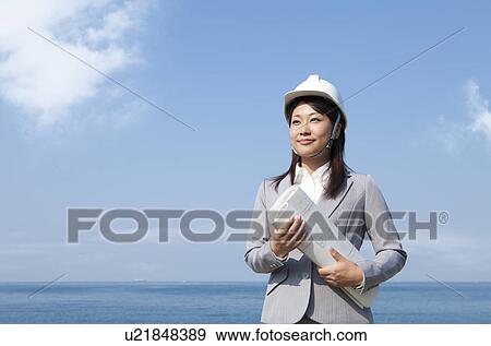 Stock Photo - Young Businesswoman with Blueprint and Hardhat. Fotosearch