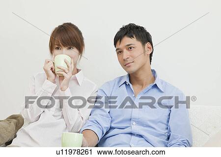 Stock Image - Young couple drinking coffee and watching TV. Fotosearch