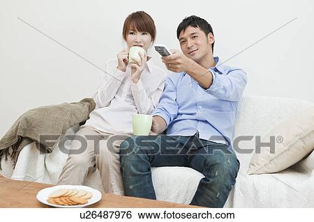 Young couple drinking coffee and watching TV View Large Photo Image Stock Photograph - Young couple drinking coffee and watching TV. Fotosearch
