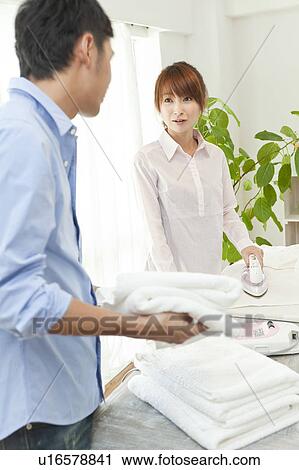 Stock Image - Young couple folding laundry and ironing. Fotosearch