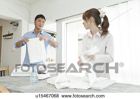 Stock Photo - Young couple folding laundry. Fotosearch