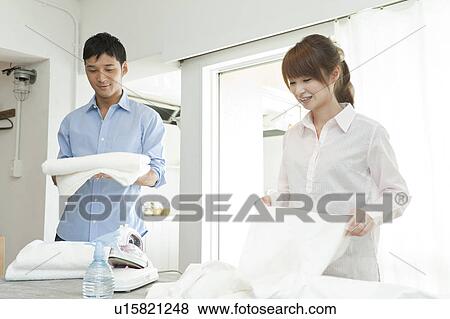 Stock Photo - Young couple folding laundry. Fotosearch