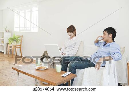 Picture - Young couple relaxing on sofa. Fotosearch
