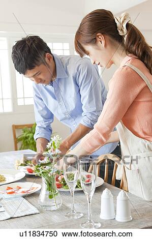 Stock Image - Young couple serving salad. Fotosearch