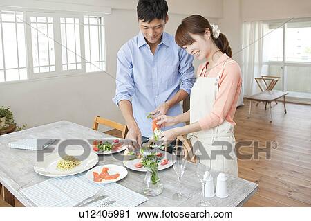Stock Image - Young couple serving salad. Fotosearch