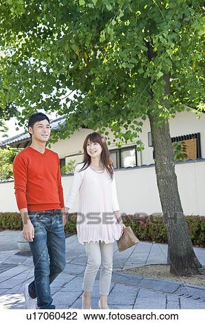 Stock Image - Young couple walking holding hands. Fotosearch