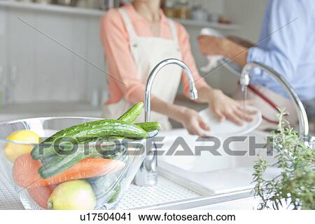 Stock Image - Young couple washing dishes. Fotosearch