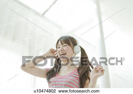 Stock Image - Young Japanese woman listening to music. Fotosearch