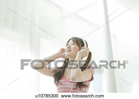 Stock Image - Young Japanese woman listening to music. Fotosearch