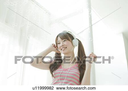 Young Japanese woman listening to music View Large Photo Image Stock Image - Young Japanese woman listening to music. Fotosearch