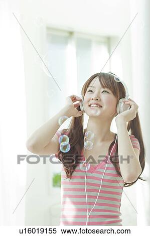 Young Japanese woman listening to music View Large Photo Image Stock Photography - Young Japanese woman listening to music. Fotosearch