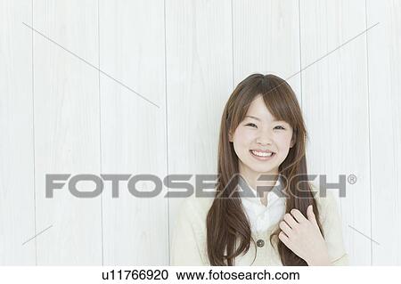 Stock Image - Young woman by wall. Fotosearch