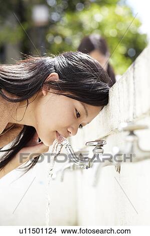 Picture - Young Woman Drinking Water From Faucet. Fotosearch