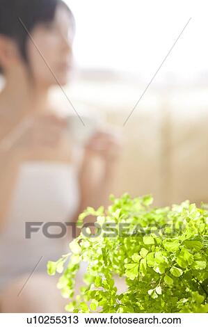 Stock Image - Young woman holding a coffee cup. Fotosearch