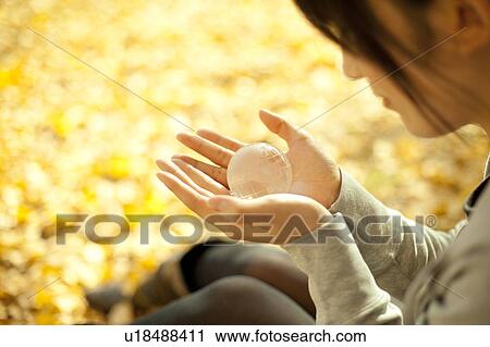Stock Image - Young woman holding a glass globe. Fotosearch