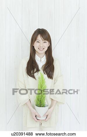Young woman holding houseplant View Large Photo Image Stock Photo - Young woman holding houseplant. Fotosearch