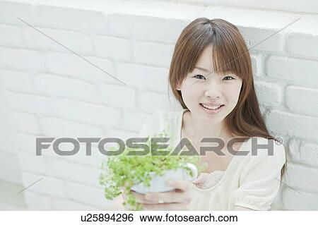 Stock Photograph - Young woman Holding Houseplant. Fotosearch