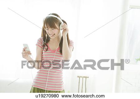Stock Image - Young woman listening to music. Fotosearch