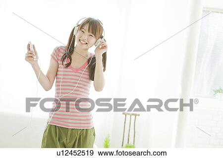Stock Photo - Young woman listening to music. Fotosearch