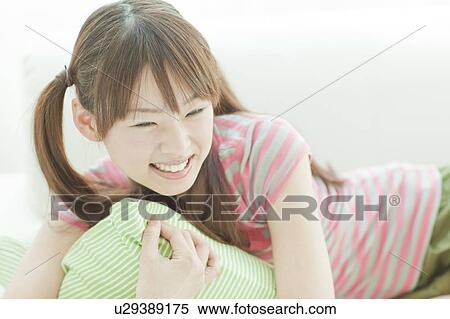 Stock Photography - Young woman lying down on sofa. Fotosearch