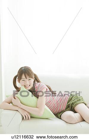 Stock Image - Young woman lying on sofa. Fotosearch