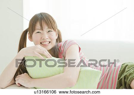 Stock Photograph - Young woman lying on sofa. Fotosearch