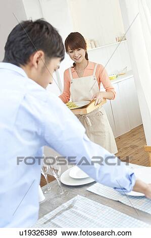 Young woman serving pasta and young man setting the table View Large Photo Image Stock Photo - Young woman serving pasta and young man setting the table. Fotosearch